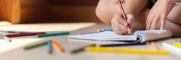 Child sitting on the floor writing