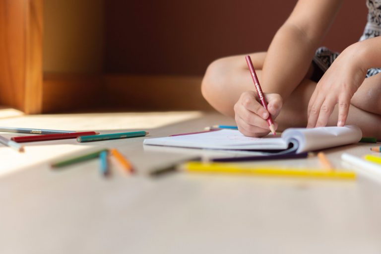 Child sitting on the floor writing